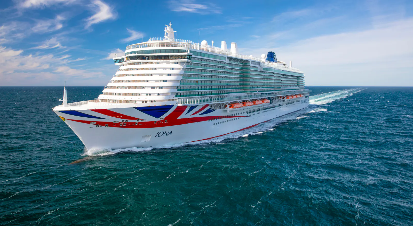 P&O’s Iona sails across open sea, with a Union Jack design on her bow.