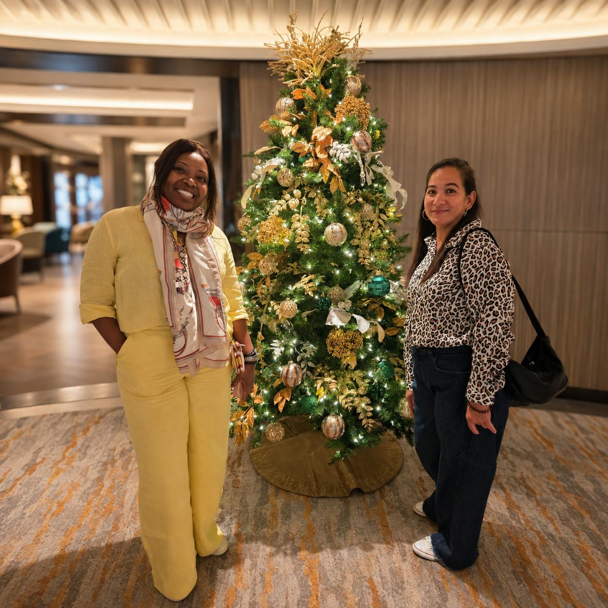 Two Limitless Travellers smiling beside a decorated Christmas tree aboard the cruise ship