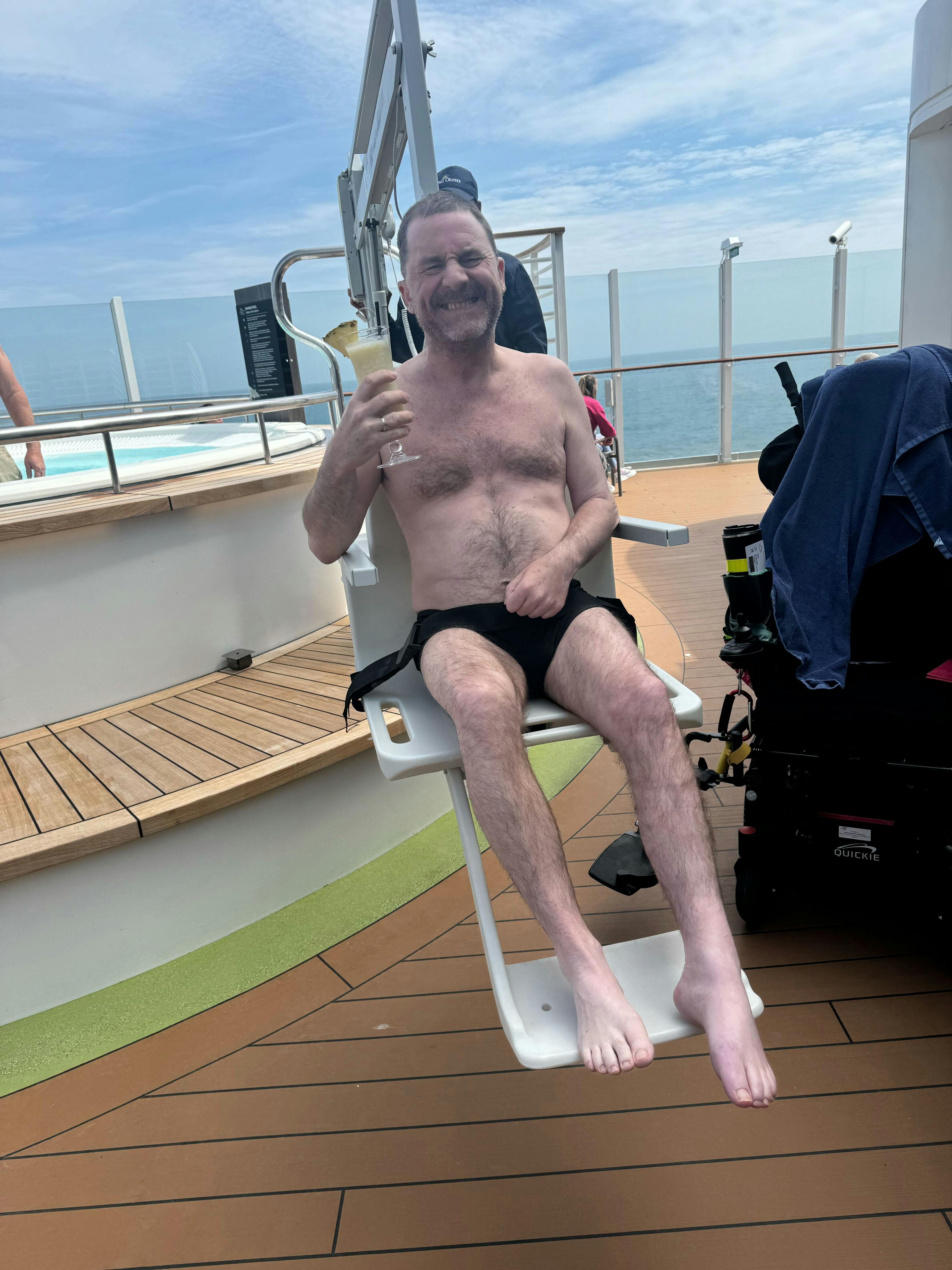 Cruise customer drink in hand being hoisted into the pool