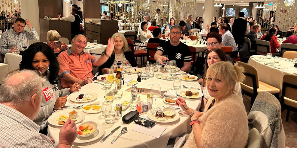 Customers and staff dining  at a restaurant together on board a cruise