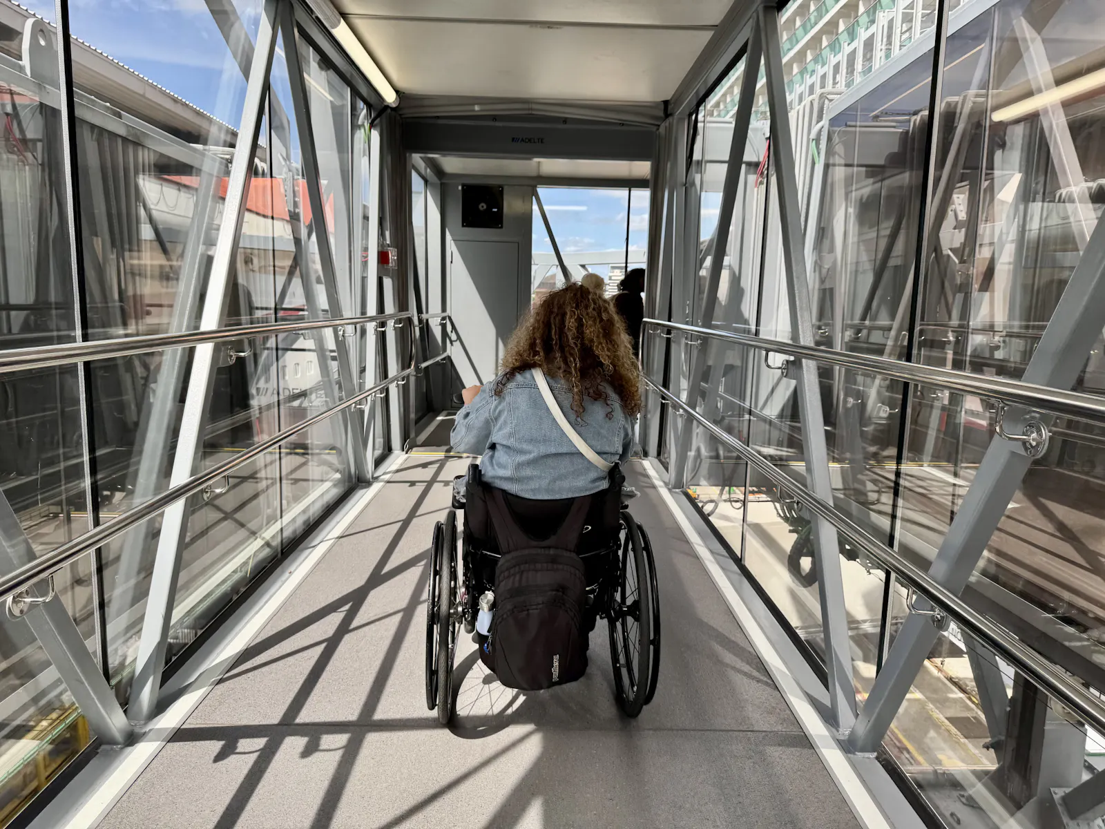 A Limitless guest in a wheelchair makes her way up a glass-sided boarding walkway onto the ship.